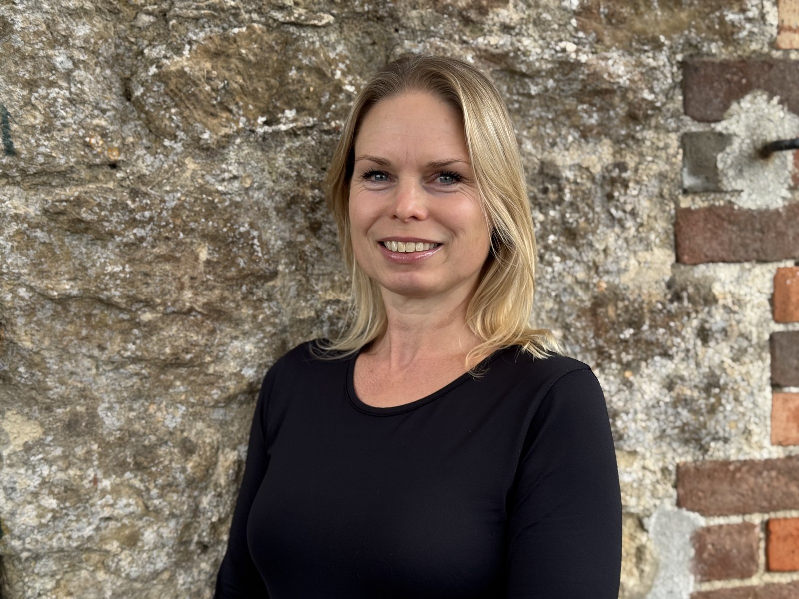 Louisa Rowlands standing beside a Cotswold stone wall