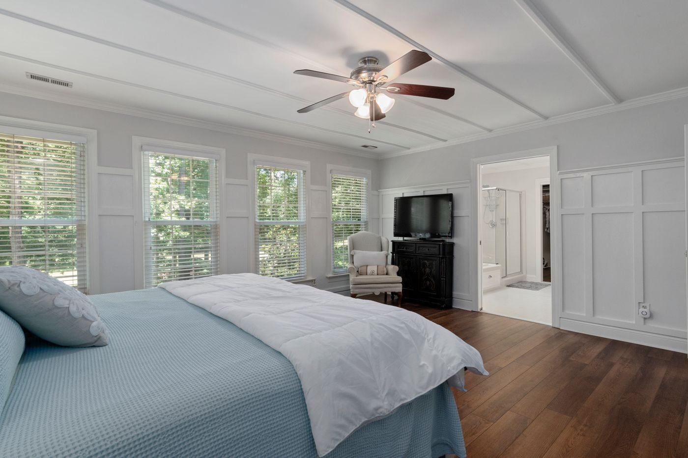 A calm bedroom with neatly dressed bedding and generous visible floor space